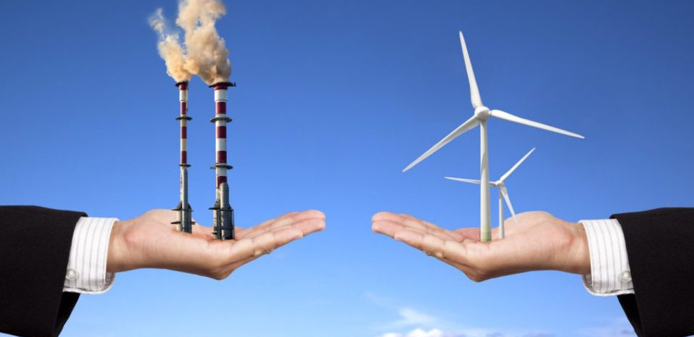 Una mano che sostiene delle turbine eoliche si oppone a un'altra mano che sostiene delle ciminiere