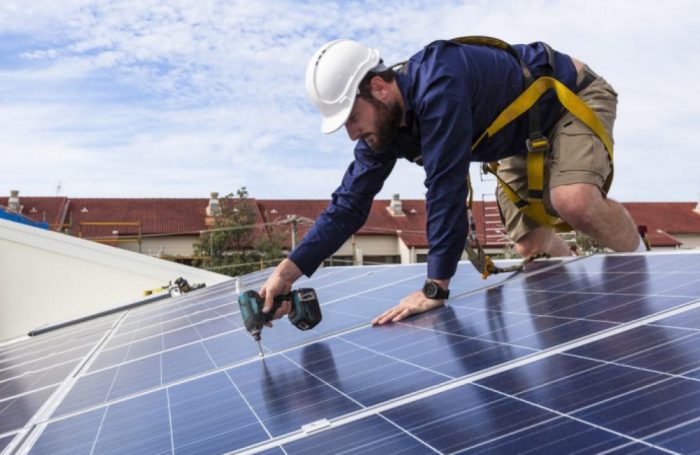 Un tecnico installa dei pannelli solari sul tetto di un edificio
